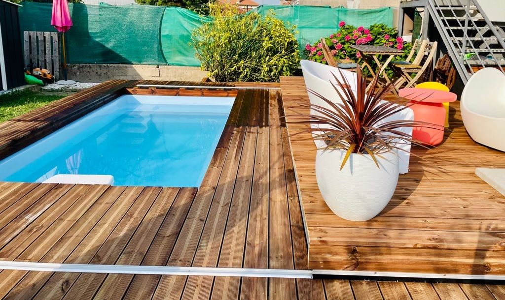 Petite piscine entourée d'une terrasse en bois, plantes et salon de jardin